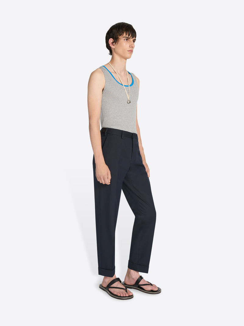 Person wearing a gray tank top and black pants on a white background