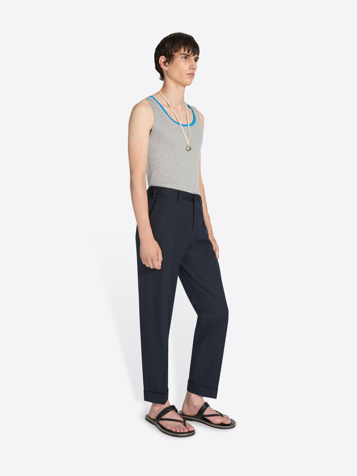 Person wearing a gray tank top and black pants on a white background