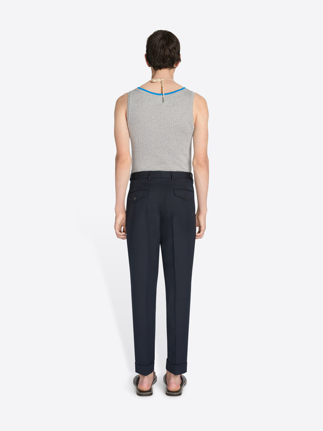 Person wearing a gray sleeveless top and black pants on a white background