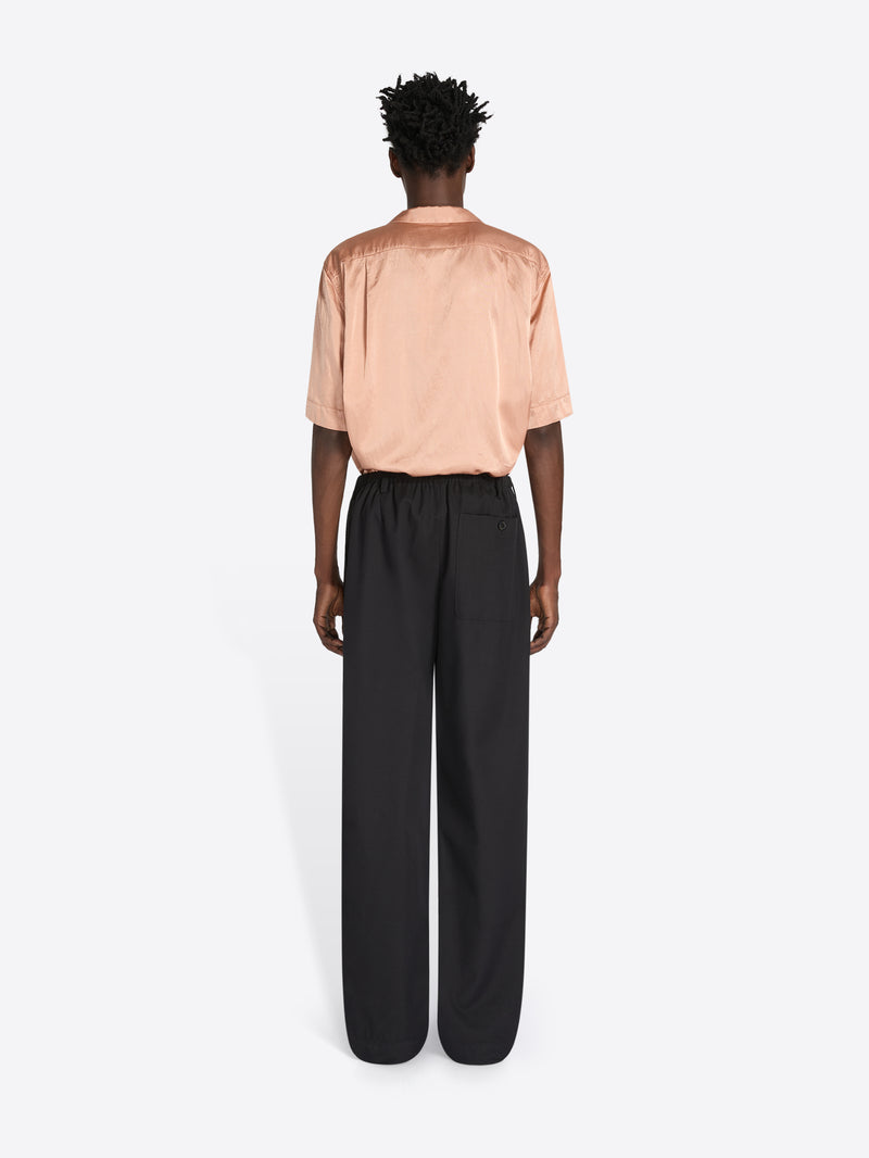 Person wearing a peach blouse and black pants on a white background