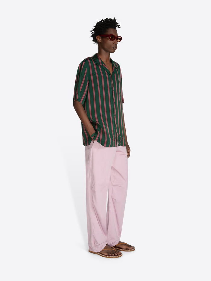 Man wearing a green and red striped shirt with pink pants on a white background