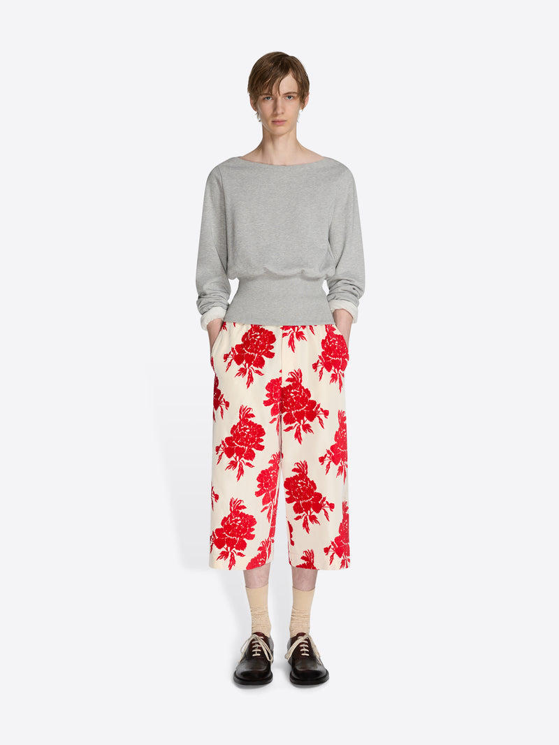 Person wearing a gray sweater and red floral pants on a white background - Dries Van Noten
