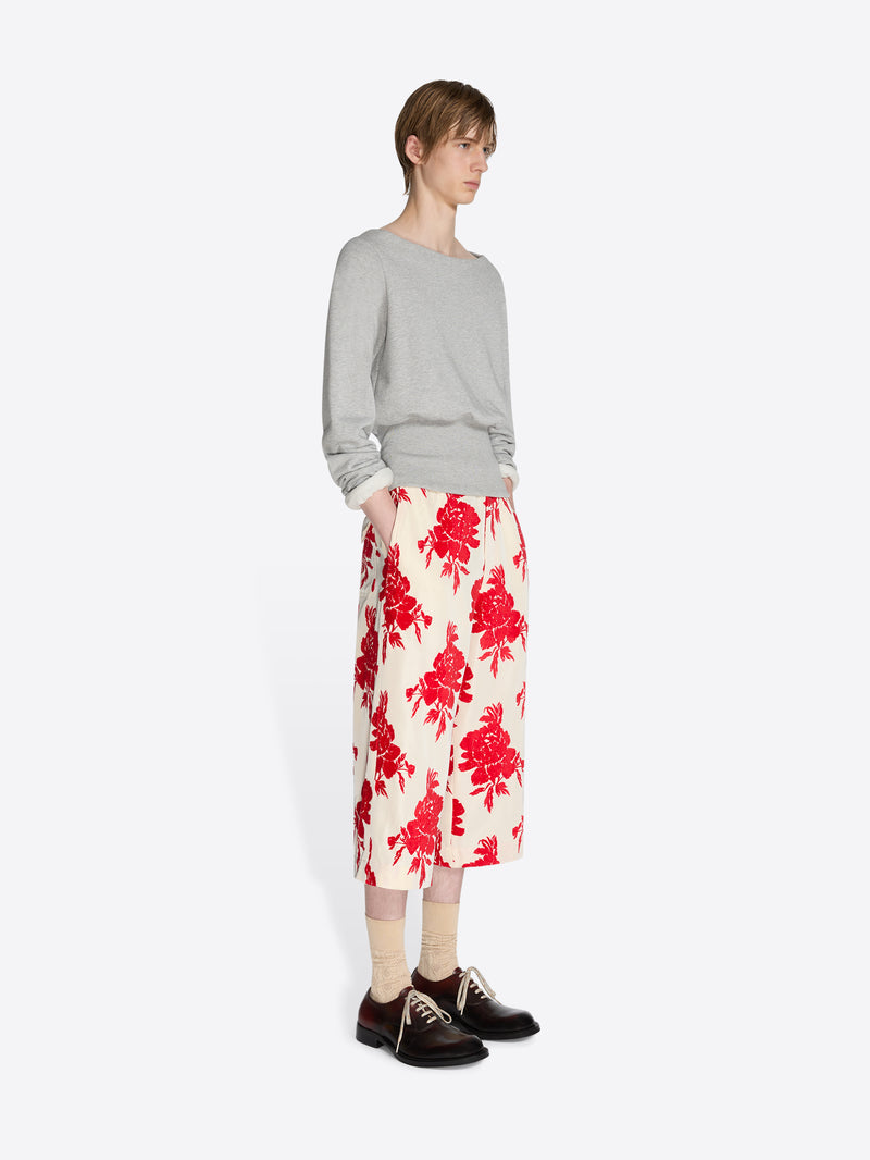 Person wearing a gray sweater and red floral skirt on a white background - Dries Van Noten