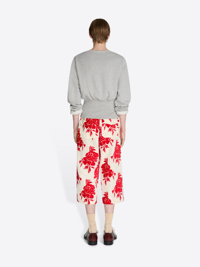 Person wearing a gray sweater and red floral pants on a white background - Dries Van Noten