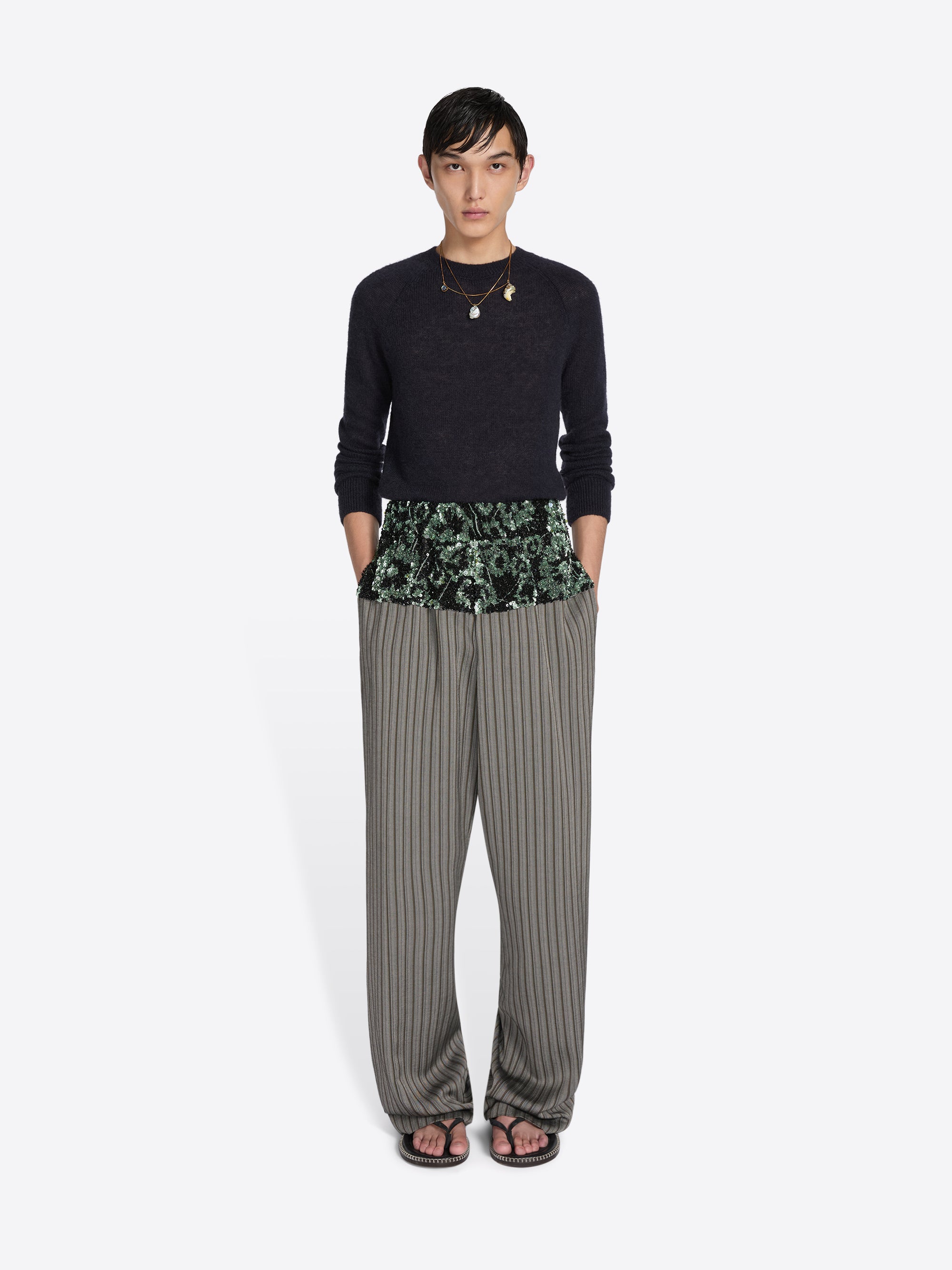 Person wearing a black top and striped pants with a floral pattern on a white background - Dries Van Noten