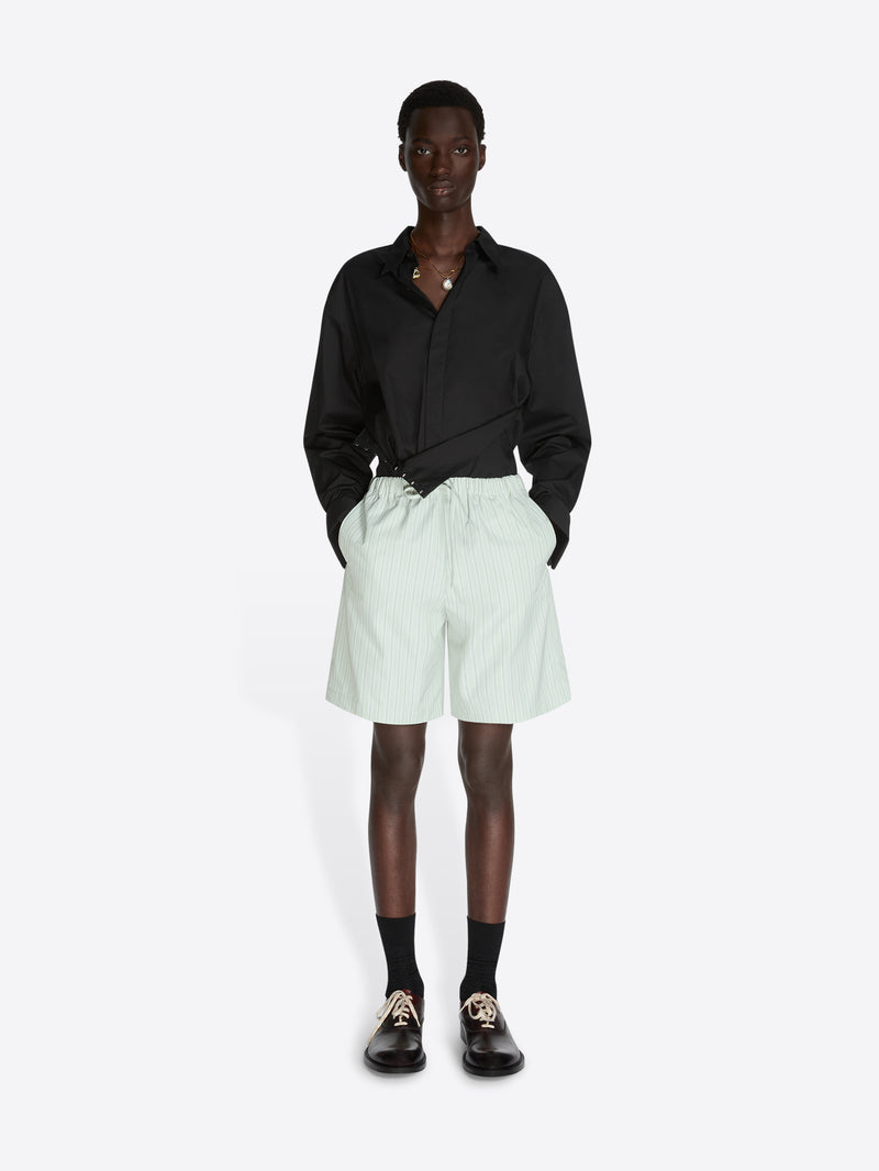 Person wearing a black shirt and light green shorts on a white background