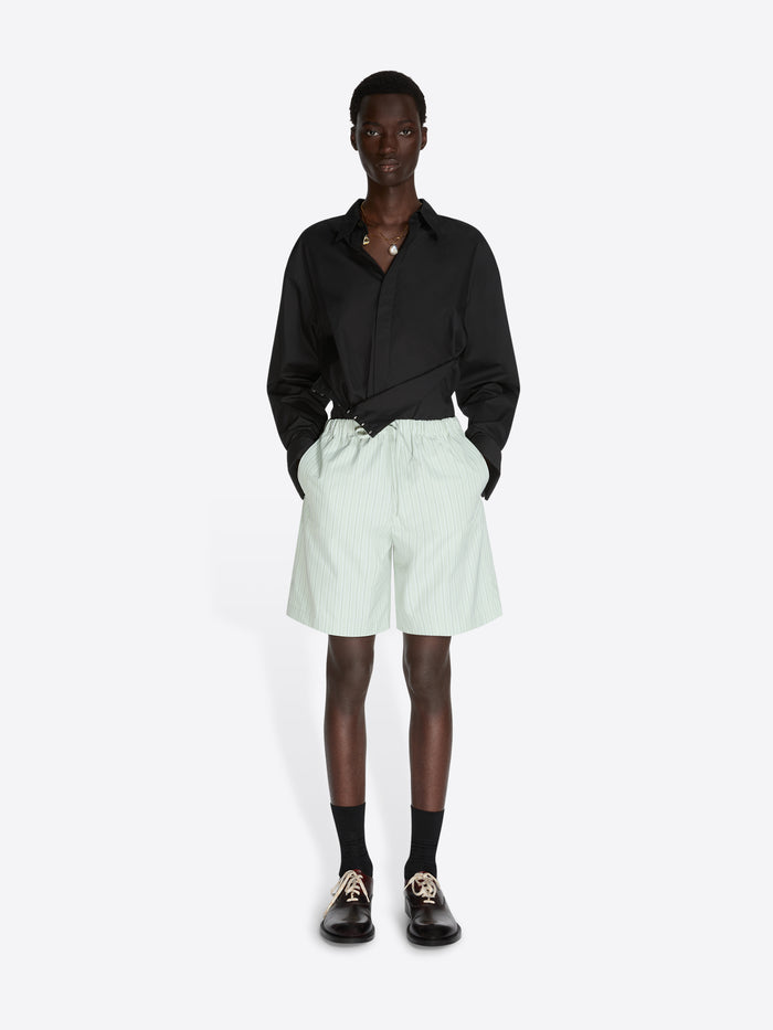 Person wearing a black shirt and light green shorts on a white background