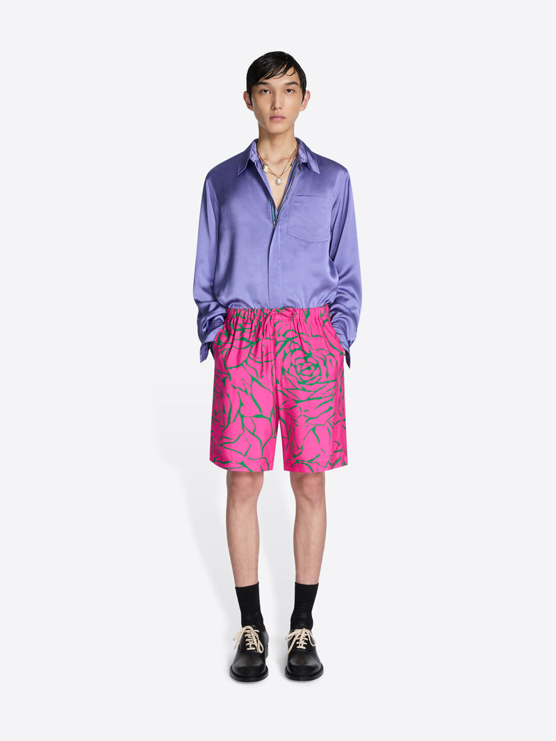 Person wearing a purple shirt and pink shorts with green patterns on a white background - Dries Van Noten