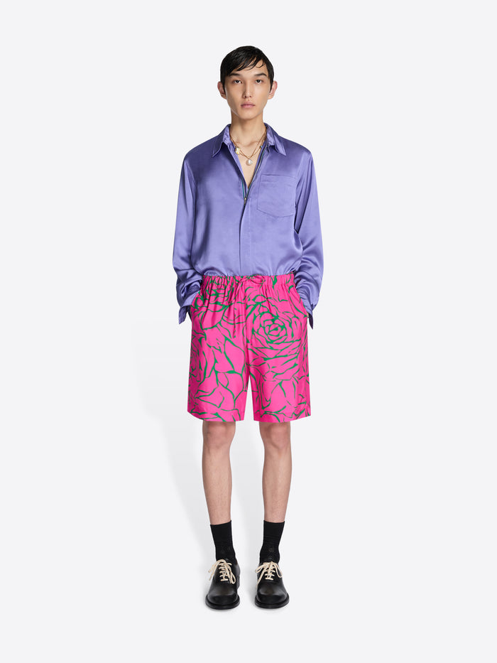 Person wearing a purple shirt and pink shorts with green patterns on a white background - Dries Van Noten