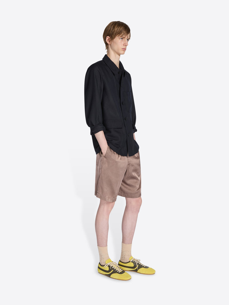 Person wearing a black shirt and beige shorts on a white background