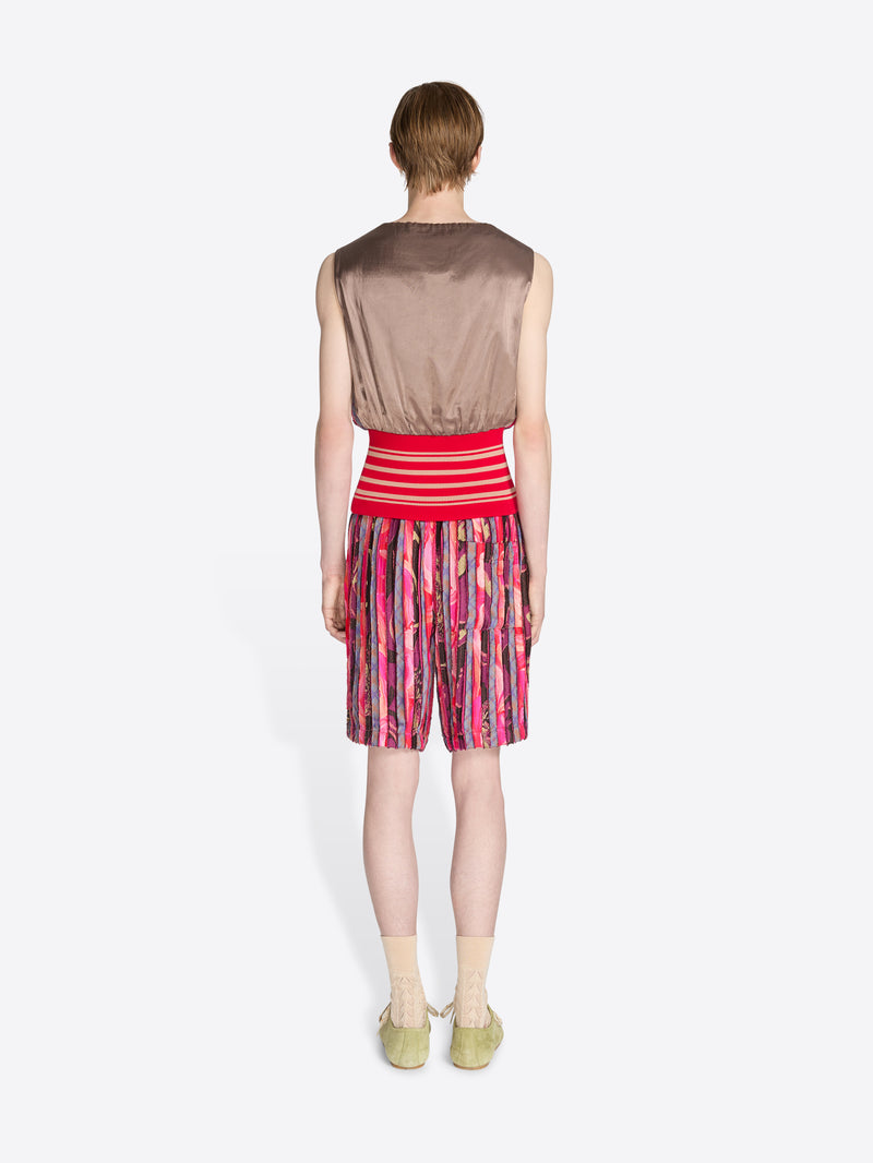 Person wearing a sleeveless brown top and red and pink striped shorts on a white background - Dries Van Noten