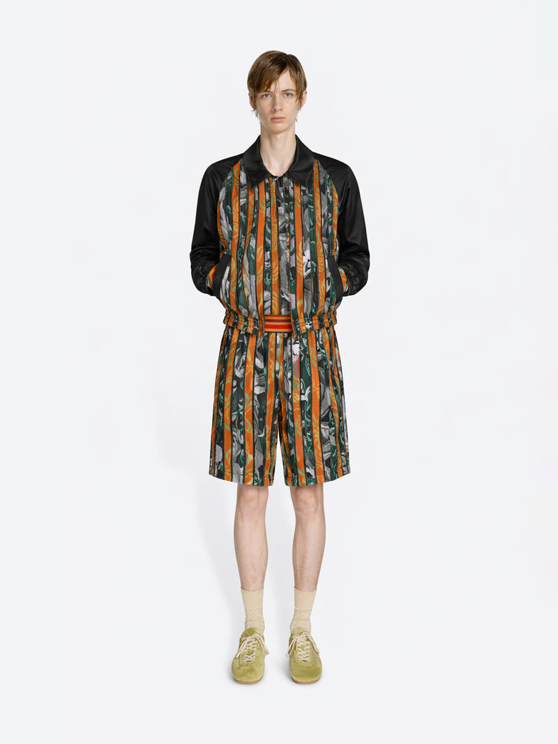 Person wearing a patterned outfit with a jacket and shorts on a white background