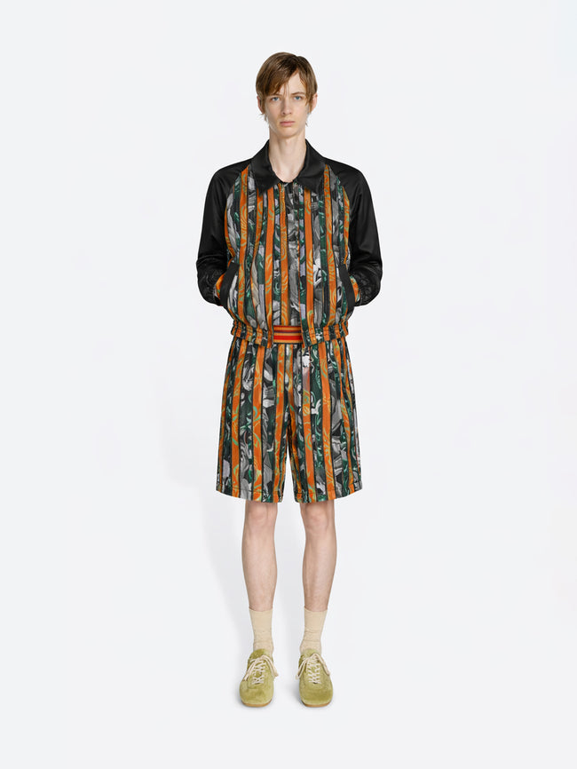 Person wearing a patterned outfit with a jacket and shorts on a white background