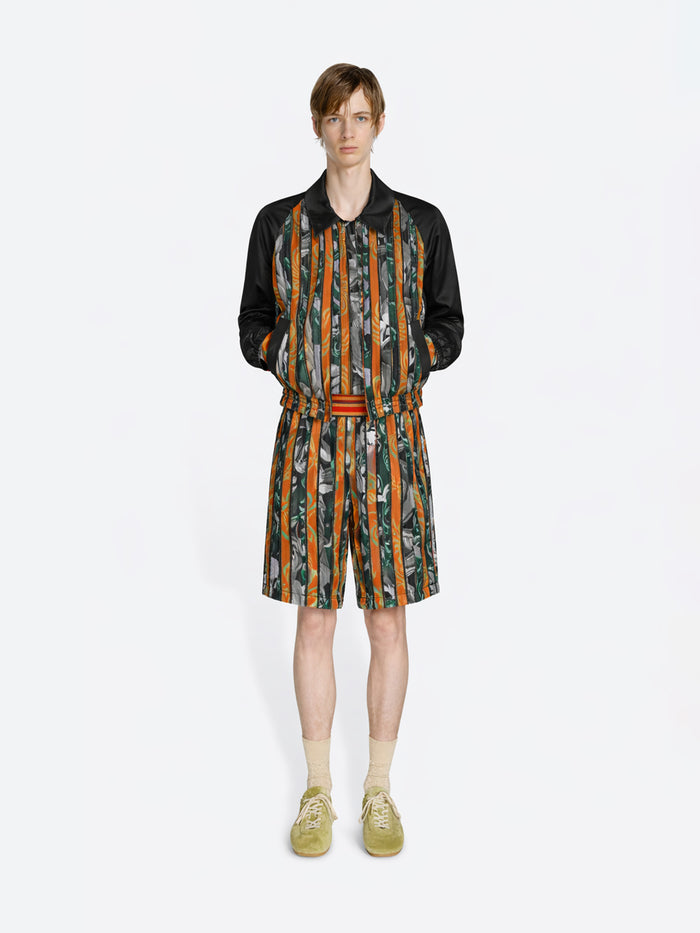 Person wearing a patterned outfit with a jacket and shorts on a white background