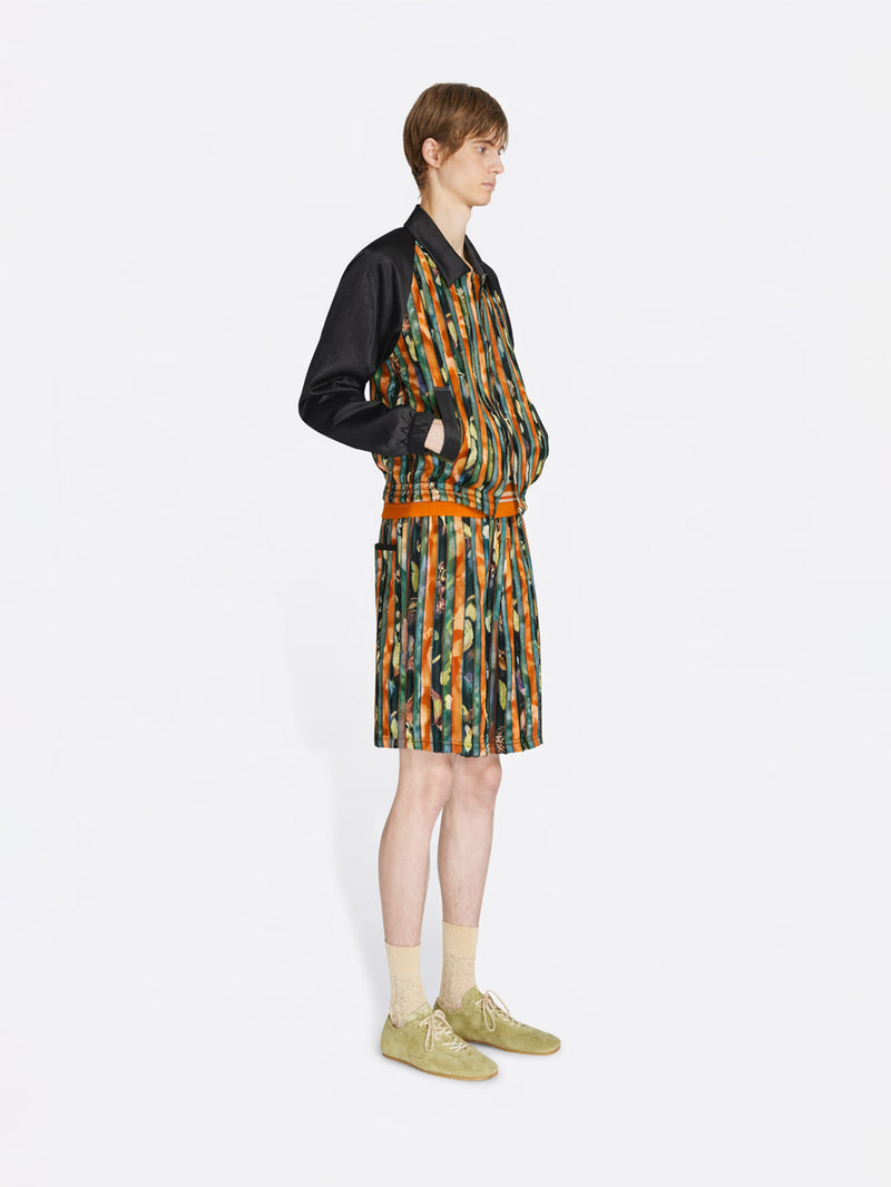 Person wearing a patterned outfit with a jacket and shorts on a white background