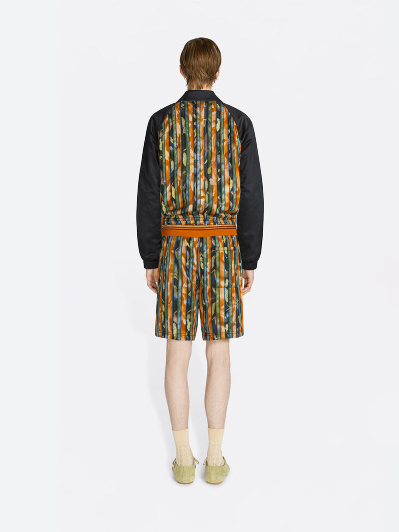 Person wearing a patterned outfit with a jacket and shorts on a white background