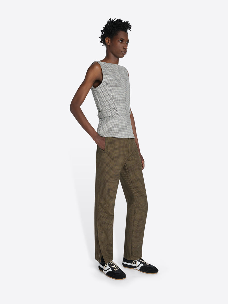 Person wearing a sleeveless gray top and brown pants on a white background - Dries Van Noten