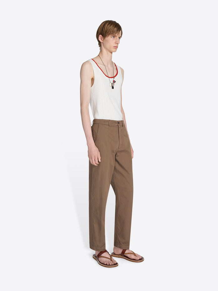 Person wearing a white tank top and brown pants on a white background