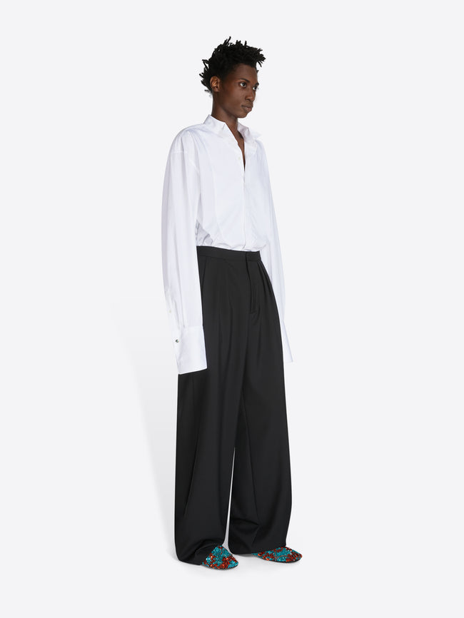 Person wearing a white shirt and black pants on a white background