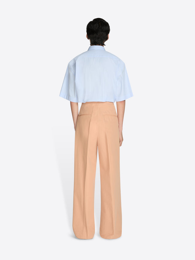 Person wearing a light blue shirt and beige pants on a white background - Dries Van Noten