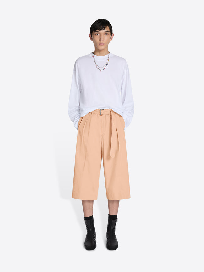 Person wearing a white shirt and beige pants on a white background