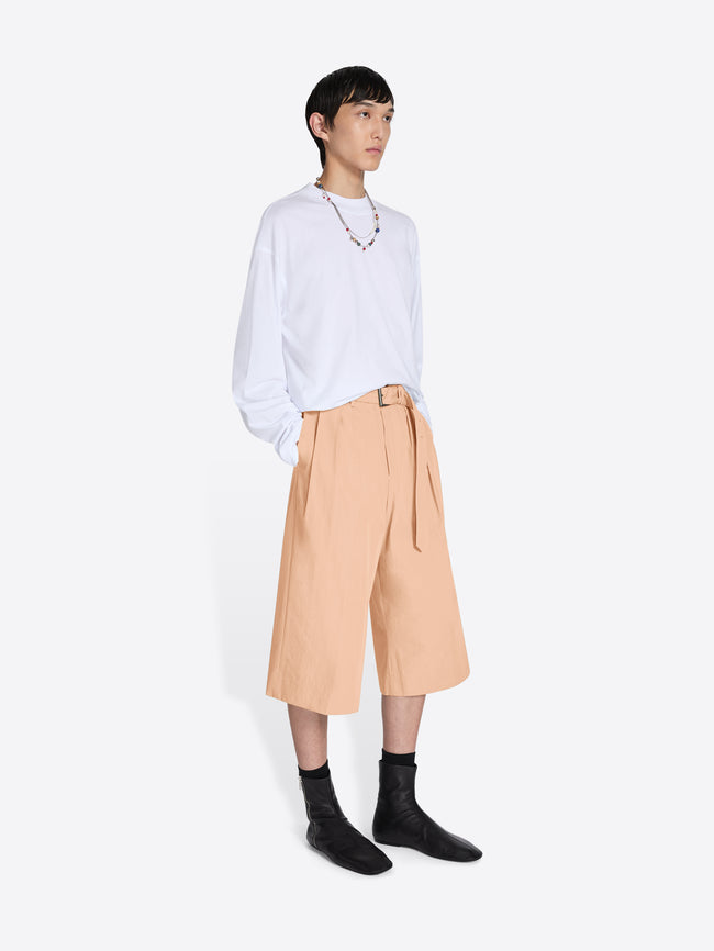 Person wearing a white shirt and beige pants on a white background