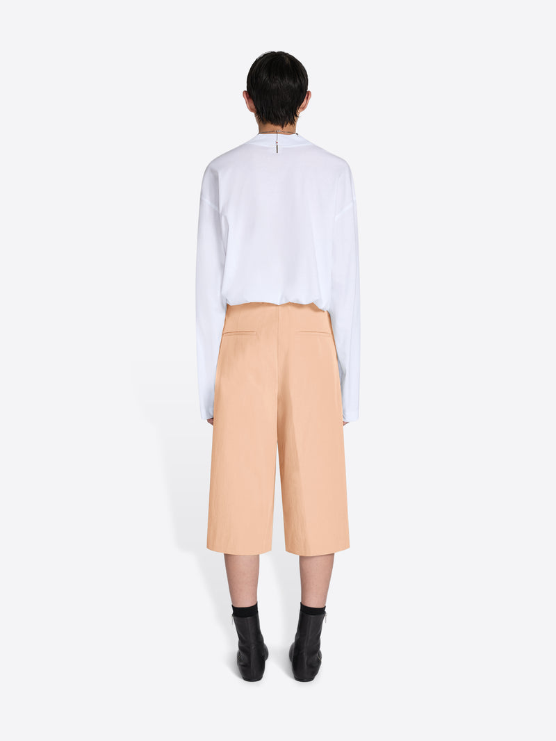 Person wearing a white shirt and beige pants on a white background