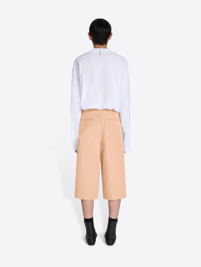 Person wearing a white shirt and beige pants on a white background