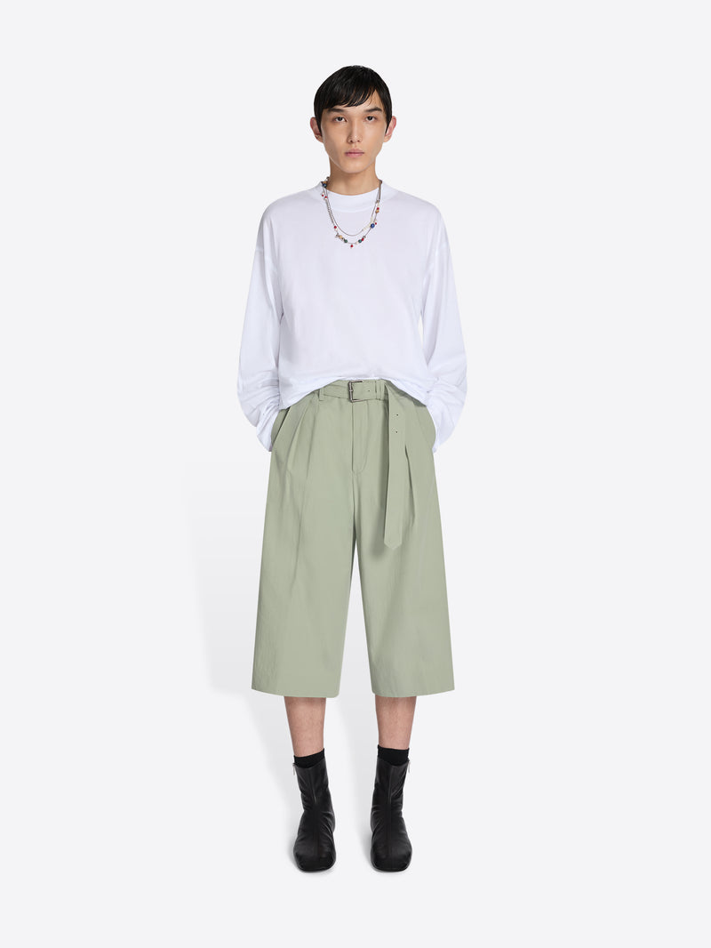 Person wearing a white shirt and light green pants on a white background