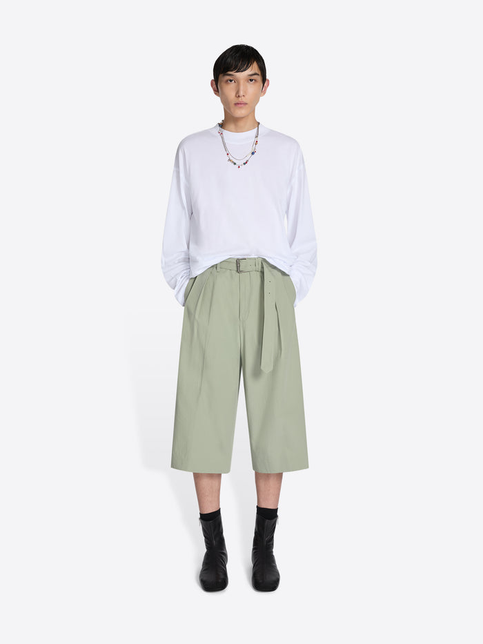 Person wearing a white shirt and light green pants on a white background