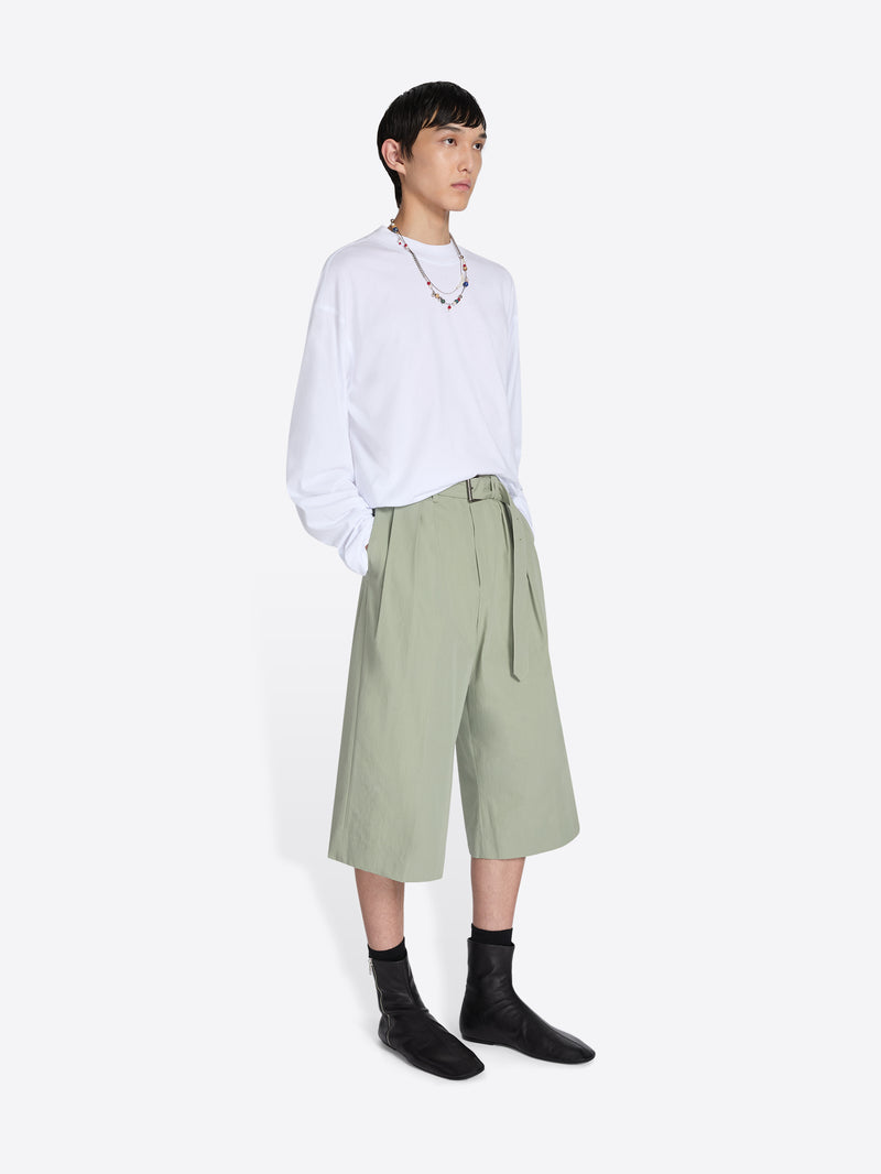 Person wearing a white shirt and green pants on a white background