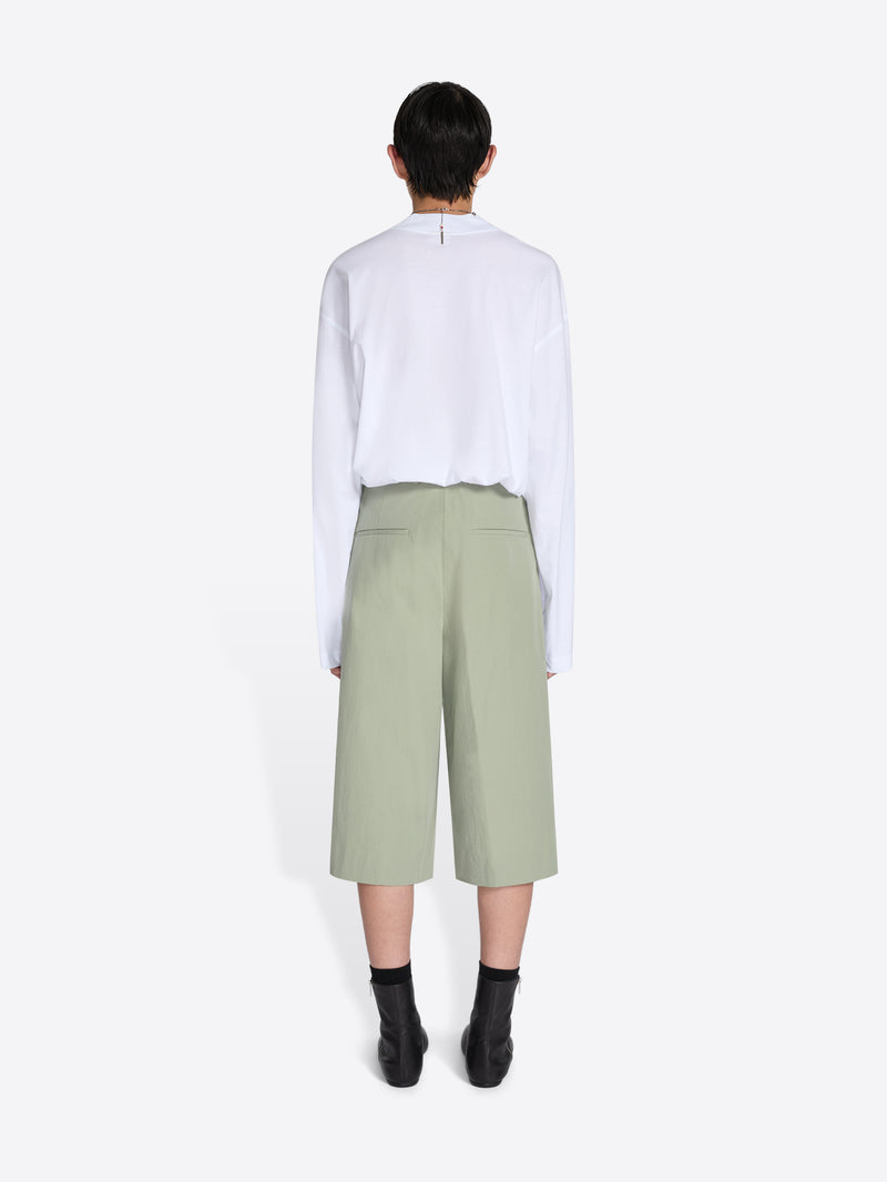 Person wearing a white shirt and light green pants on a white background