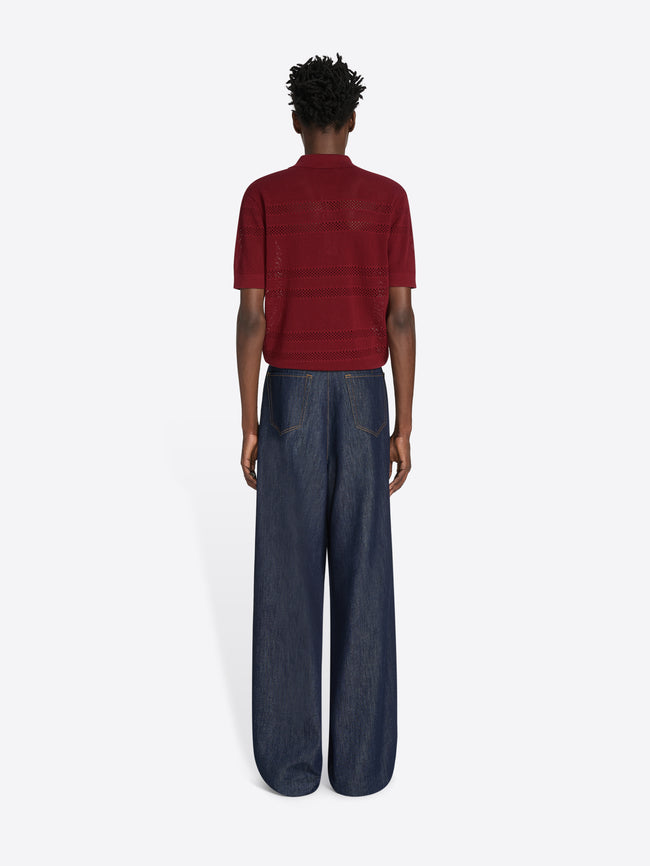 Person wearing a red striped shirt and dark blue jeans on a white background - Dries Van Noten