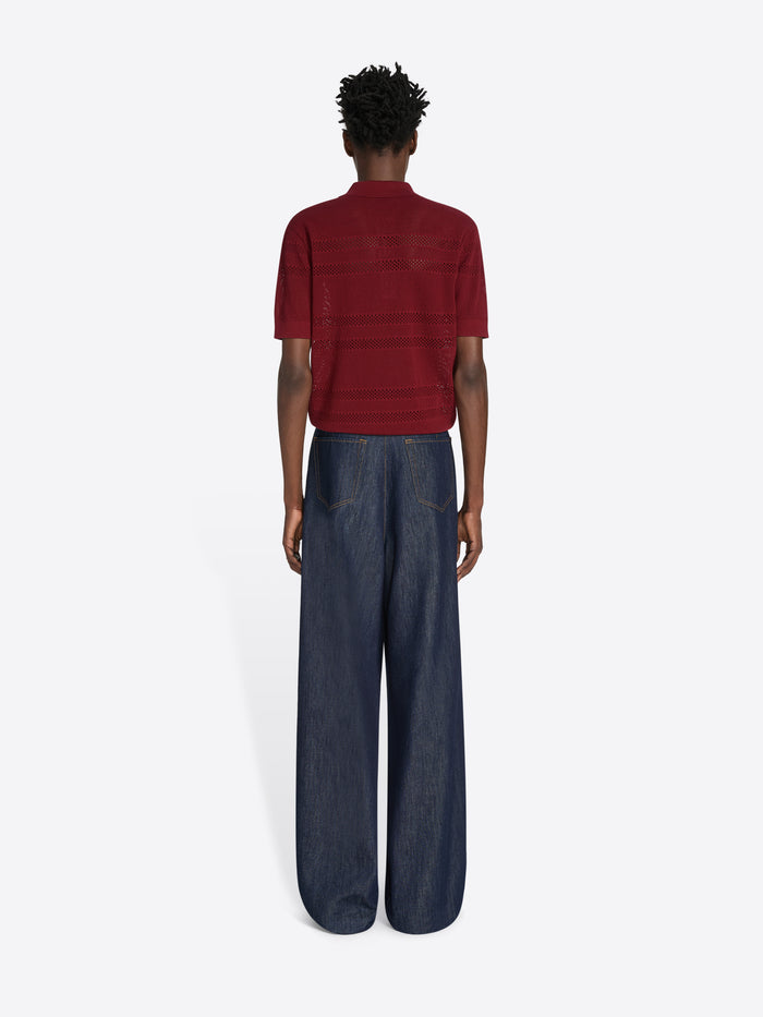 Person wearing a red striped shirt and dark blue jeans on a white background - Dries Van Noten