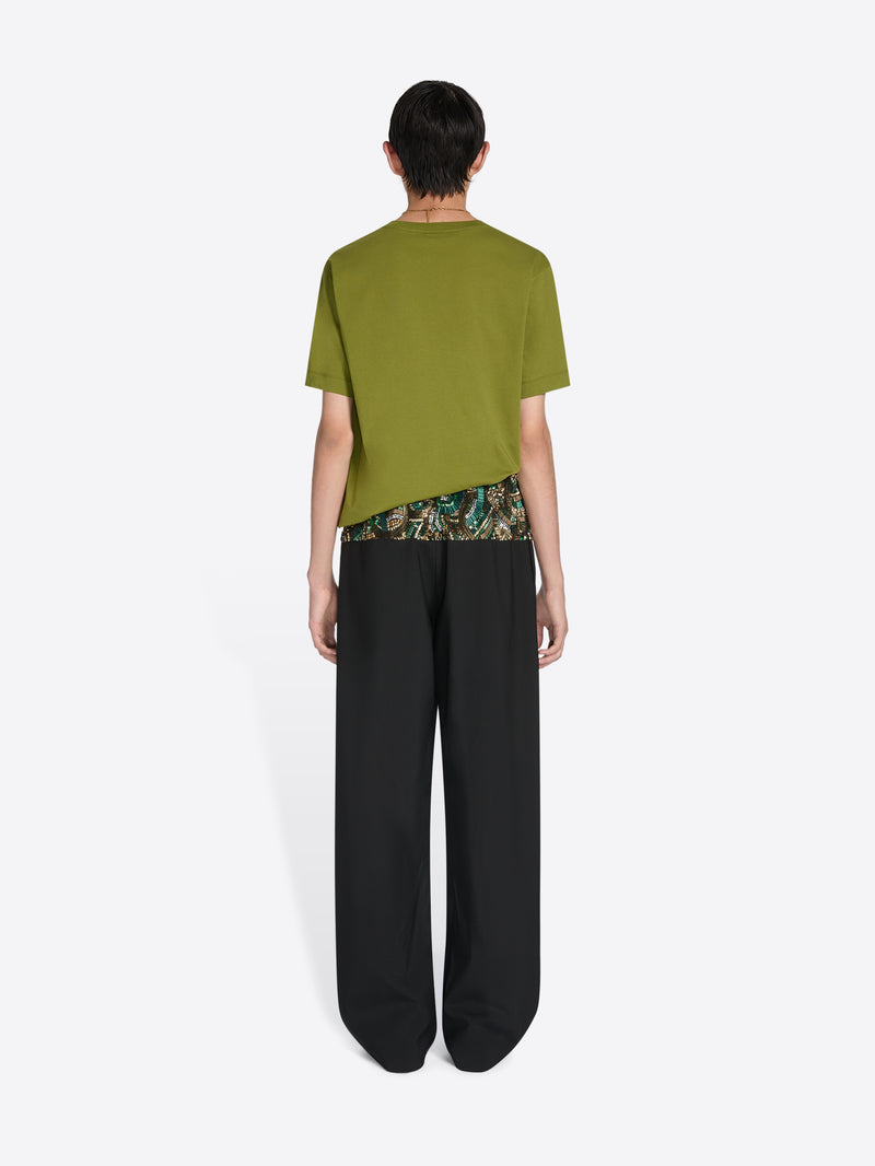 Person wearing a green t-shirt with a camouflage pattern and black pants on a white background