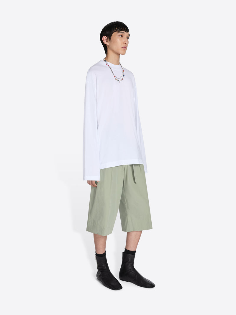 Person wearing a white shirt and green shorts on a white background