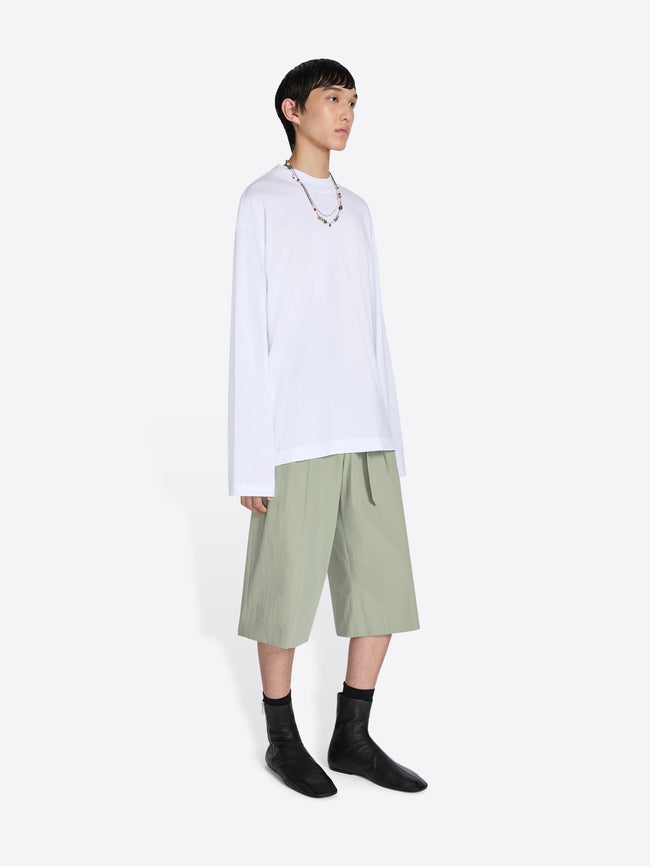 Person wearing a white shirt and green shorts on a white background