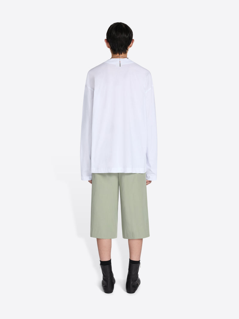 Person wearing a white shirt and light green pants on a white background