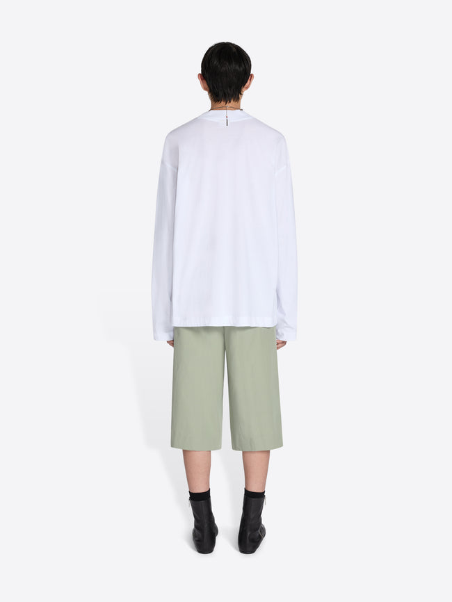 Person wearing a white shirt and light green pants on a white background