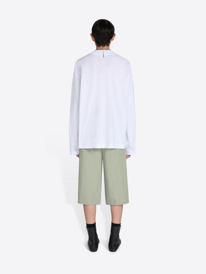 Person wearing a white shirt and light green pants on a white background