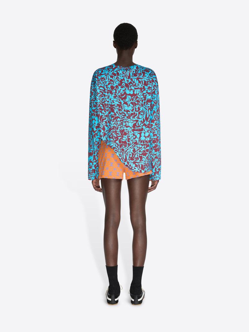 Person wearing a colorful patterned dress with an orange skirt on a white background