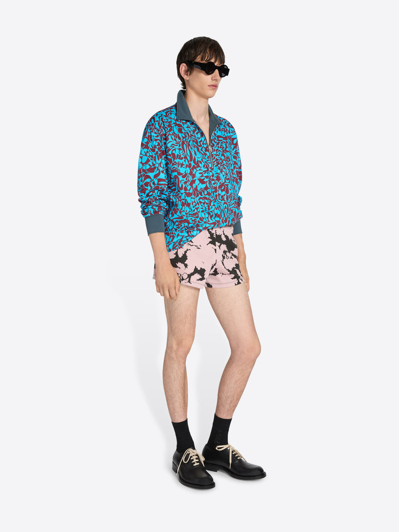 Person wearing a colorful floral shirt and shorts on a white background