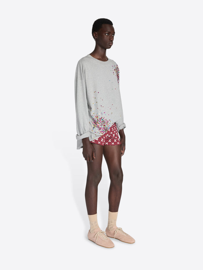 Person wearing a light gray sweatshirt with floral design and red shorts on a white background - Dries Van Noten