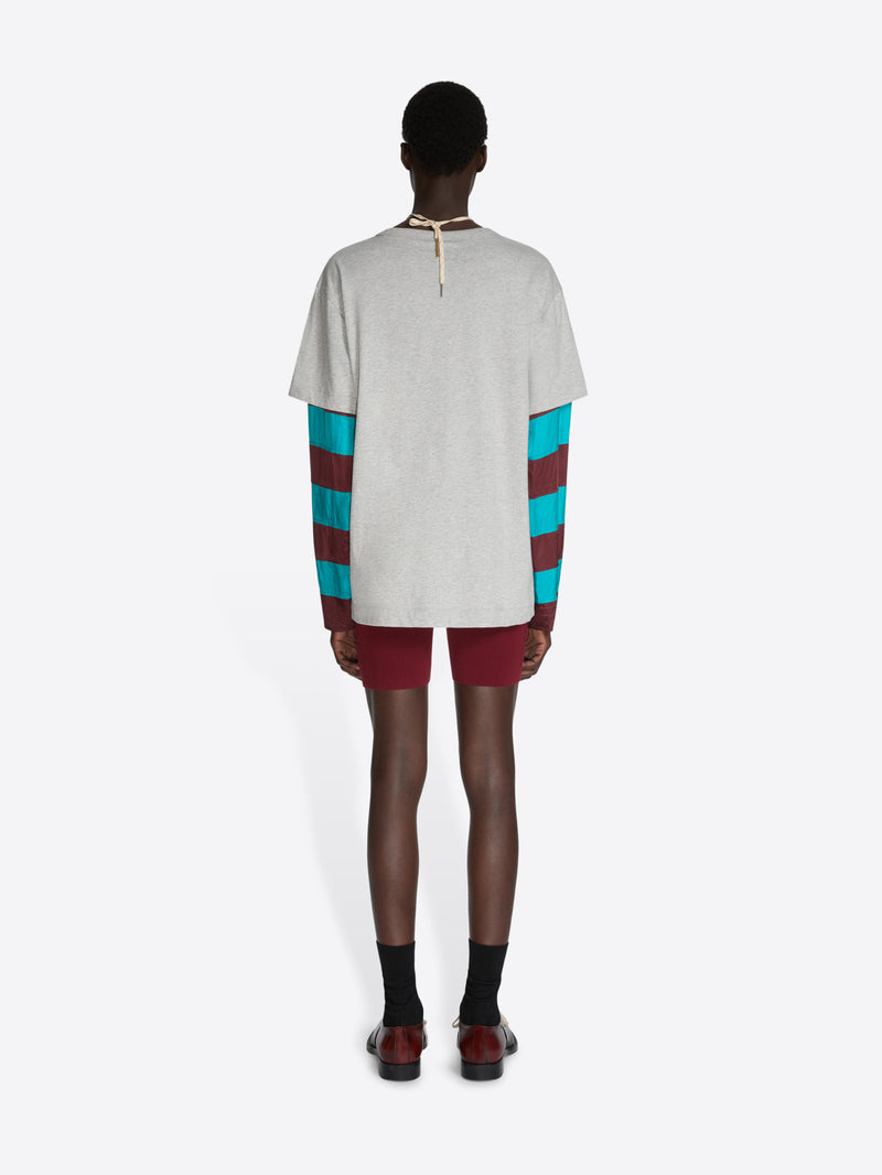 Person wearing a white t-shirt with colorful sleeves and maroon shorts on a white background