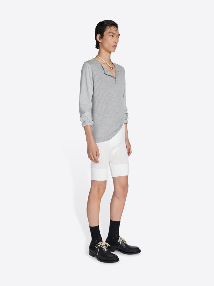 Person wearing a gray sweater and white shorts on a white background - Dries Van Noten