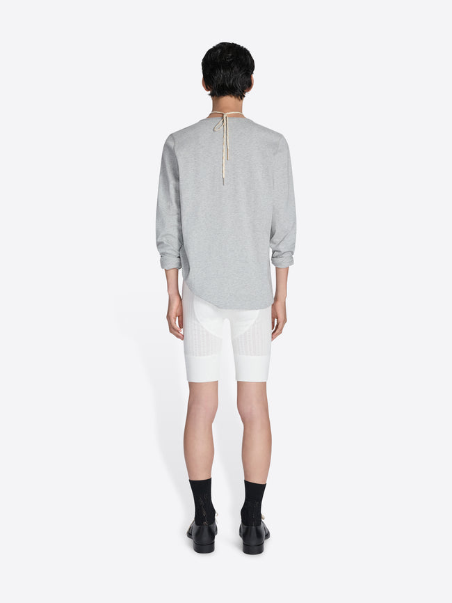 Person wearing a gray long-sleeve shirt and white shorts on a white background - Dries Van Noten