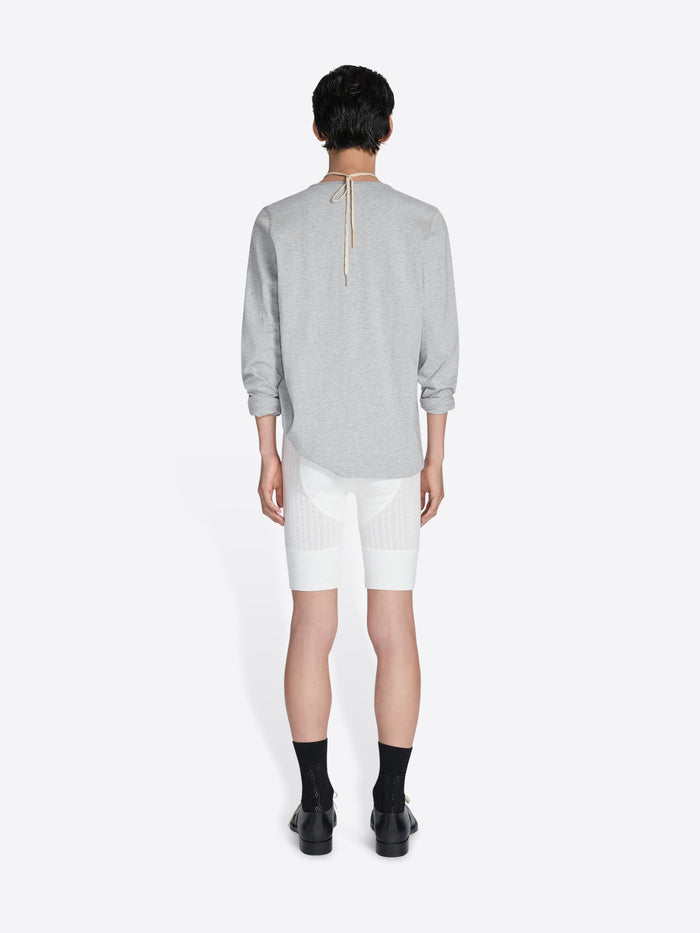 Person wearing a gray long-sleeve shirt and white shorts on a white background - Dries Van Noten