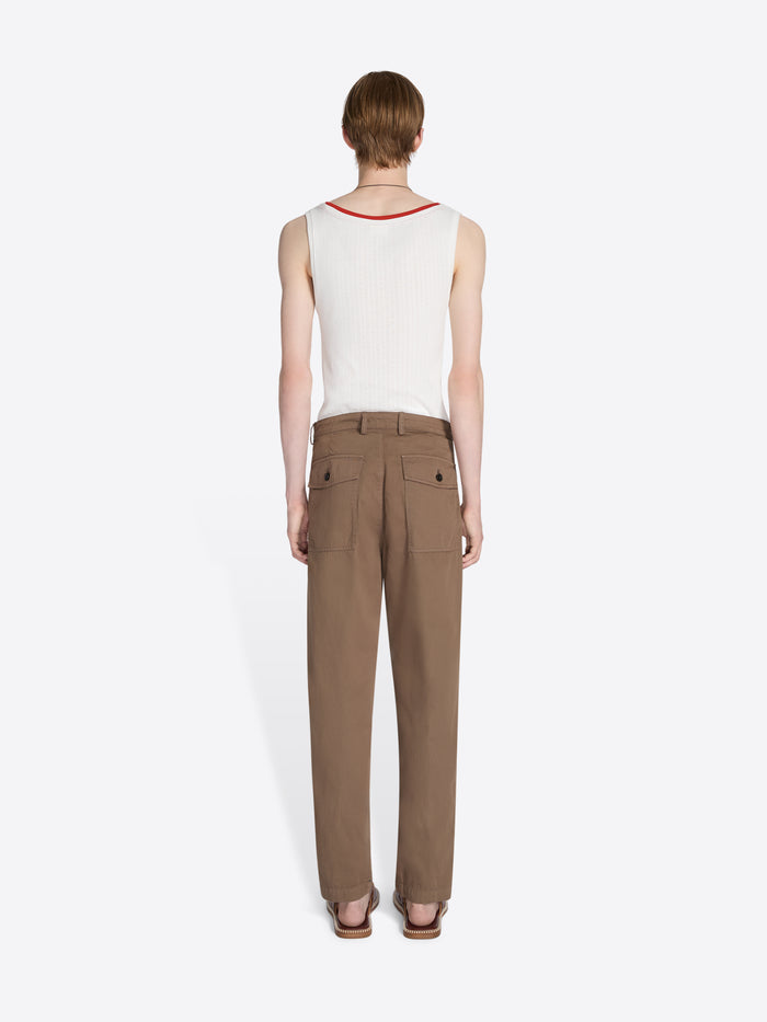 Person wearing a white sleeveless top and brown pants on a white background - Dries Van Noten