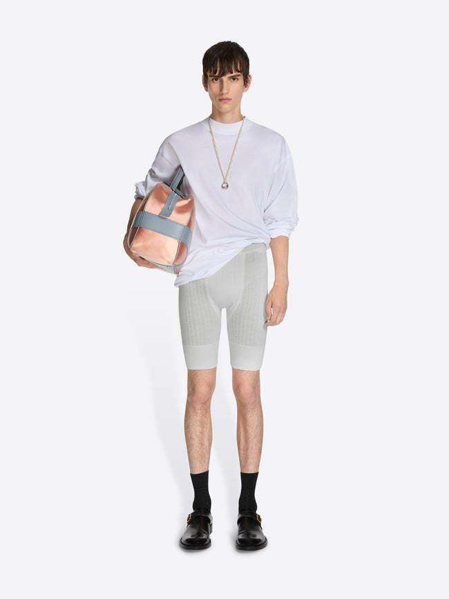 Person wearing a white shirt, gray shorts, and black shoes holding a pink bag on a white background - Dries Van Noten