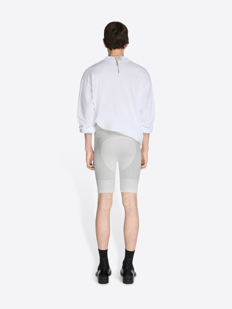 Person wearing a white shirt and light gray shorts on a white background - Dries Van Noten